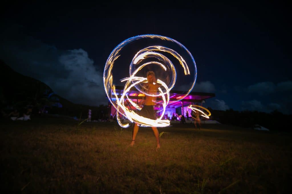 fire spinner outdoors in a field making a beautiful pattern in the air at a movement event