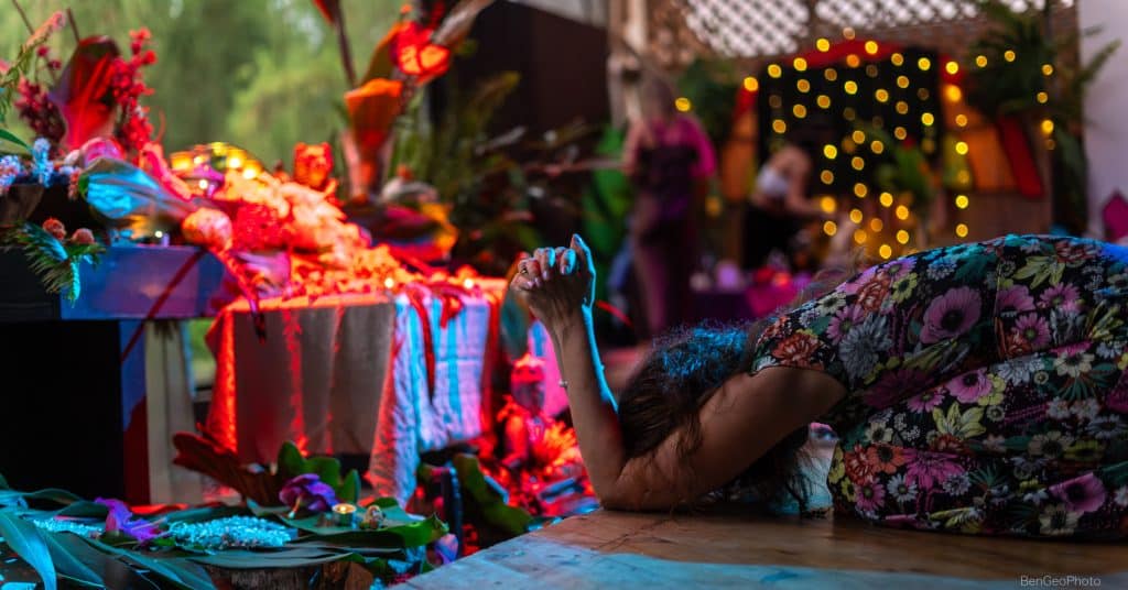 woman kneeling down and praying in front of a flower altar at a movement event