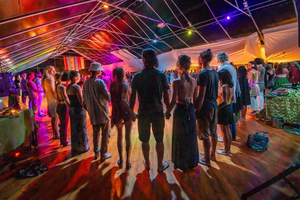 group of men and women standing in a circle and holding hands during a ceremony at a movement event