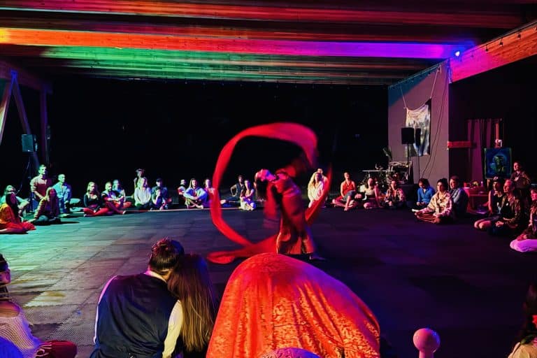 woman dancing with flowing ribbons in trhe air in the center of a circle of seated people